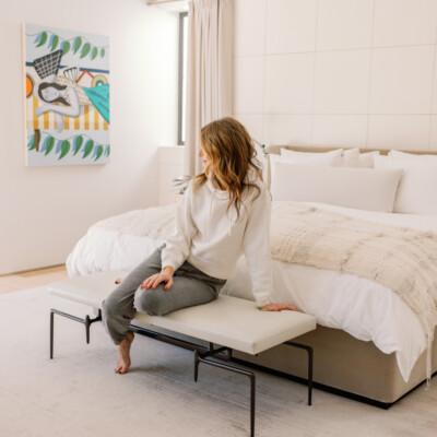 Candace Nelson wearing loungewear sitting on bed.