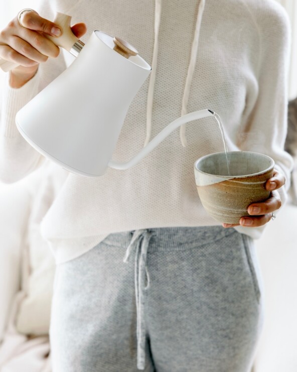 Pouring water from white electric tea kettle.