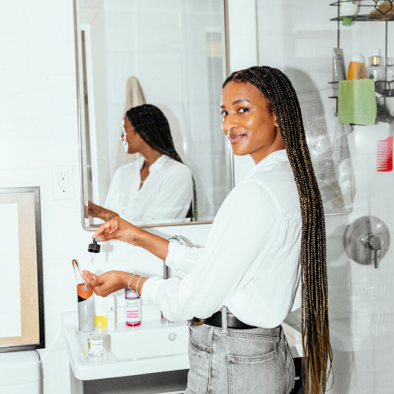 Woman applying face oils in bathroom.